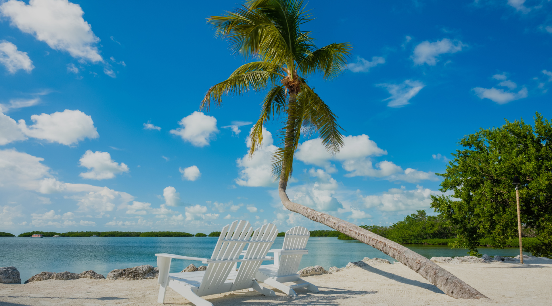Adirondack chairs on a Florida Keys beach with palm tree and turquoise water